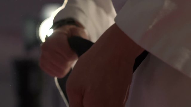 Close up of taekwondo arts athlete tying the knot to his black belt in the gym