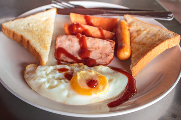 Breakfast with fried eggs, ham and sausages.