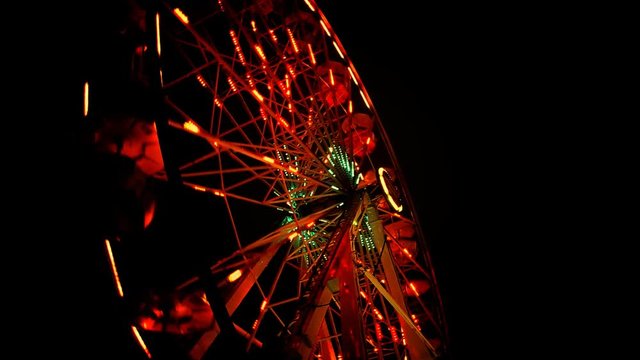 A ferris wheel spins in the dark.