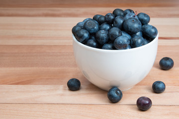 Blueberries in a white bowl on a wood table
