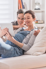 At home, pregnant woman and her husband using a digital tablet