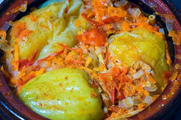 fragrant stuffed baked bell peppers in a clay pot, top view.