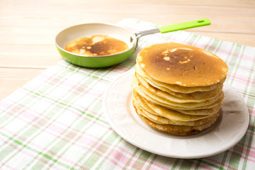 Stack of homemade breakfast pancakes and green pan