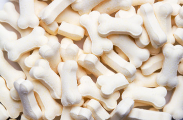 Pile of white color dog biscuits in the shape of a bone for a pet food background