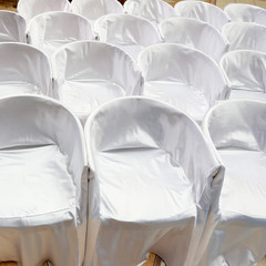 Chairs covered with white cloth on wedding ceremony