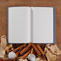 open old vintage book with spices on wooden background.