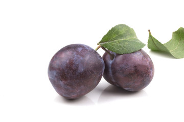 two ripe blue ripe plums with leaves