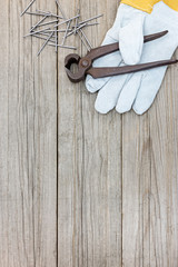 working gloves with nails and pincers on grey wooden boards background