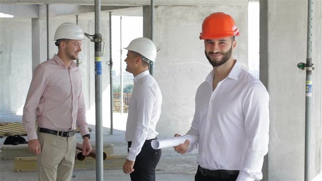 Male builder holds set of plans of building under construction