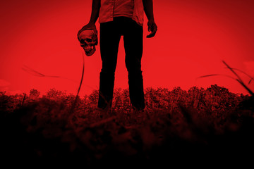 Release evil,Person with human skull in hand,Scary background for halloween and book cover ideas