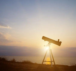 Naklejka premium telescope silhouette at sunset background