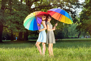Two pretty ladies holding colorful umbrellas