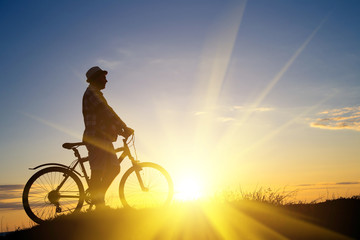 Fototapeta na wymiar Silhouette of sports person cycling on the field on the beautifu