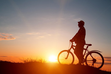 Obraz na płótnie Canvas Silhouette of sports person cycling on the field on the beautifu