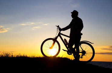 Plakat Silhouette of sports person cycling on the field on the beautifu