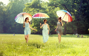 Three cheerful ladies walking on the summer meadow