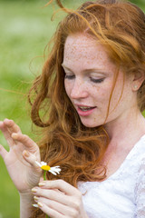 Beautiful woman enjoying daisy field, nice female in the meadow of flowers, pretty girl relaxing outdoor, having fun,holding plant, happy young lady and spring green nature, harmony concept