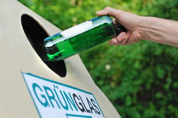 Mensch entsorgt eine Glasflasche in einem Altglas-Container