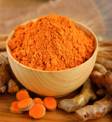 Turmeric and turmeric powder on wooden background