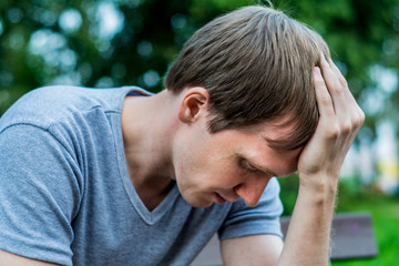 A man sits on a bench. He is sad and pensive.
