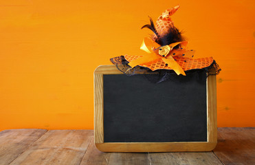 Halloween concept. Cute witch hat next to blank blackboard