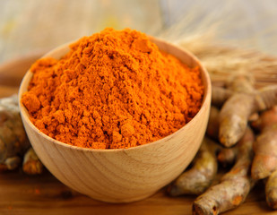 Turmeric and turmeric powder on wooden background