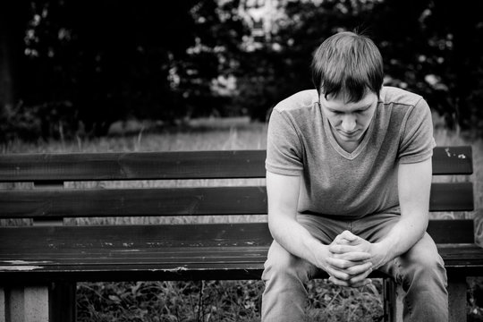 A man sits on a bench. He is sad and pensive.
