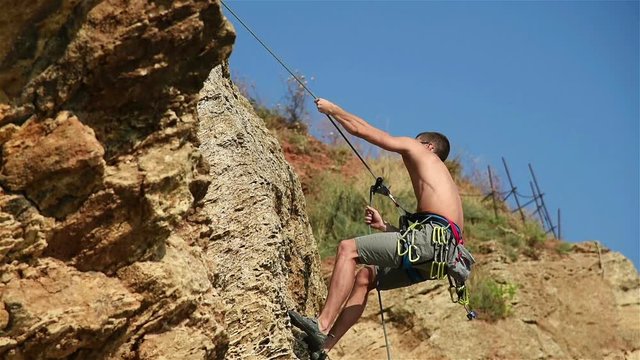 Extreme Rock Climber Climbing A Rope From A Cliff