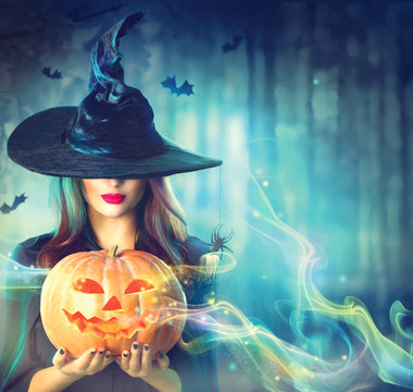 Witch with a Halloween pumpkin in a dark forest