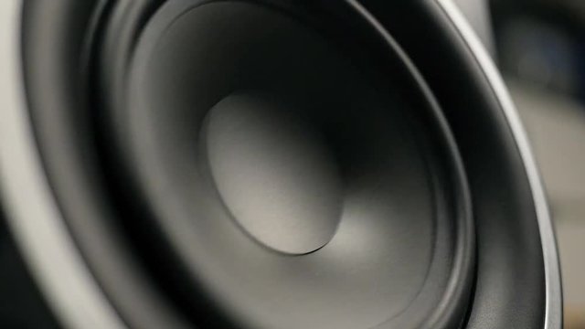 A close up of large subwoofer moving.