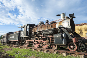 Rusted old steam engine of an old-fashioned locomotive train, originally used in the sugar industry, sitting on the tracks on the outskirts of Trinidad, Cuba