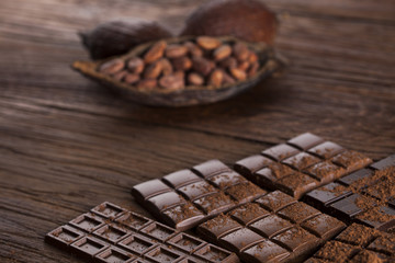 Dark homemade chocolate bars and cocoa pod on wooden