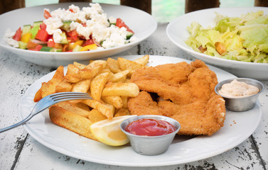 Food with potatoes and chicken schnitzel on textural wooden table