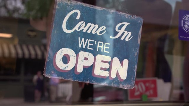 Shop owner flipping an open sign over