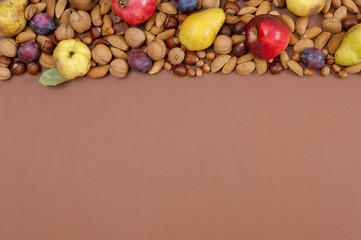 Autumn fruits and nuts on brown background with copy space