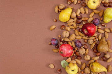 Autumn fruits and nuts on brown background with copy space
