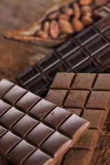 Dark homemade chocolate bars and cocoa pod on wooden