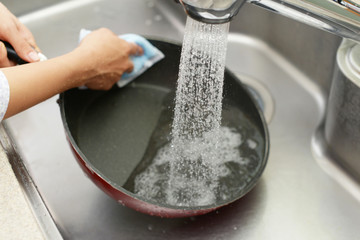 フライパンを洗う女性