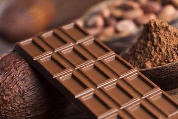 Chocolate bar, candy sweet, cacao beans and powder on wooden bac