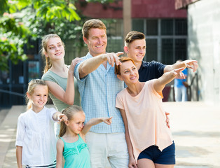 Portrait of ordinary large family standing pointing with finger