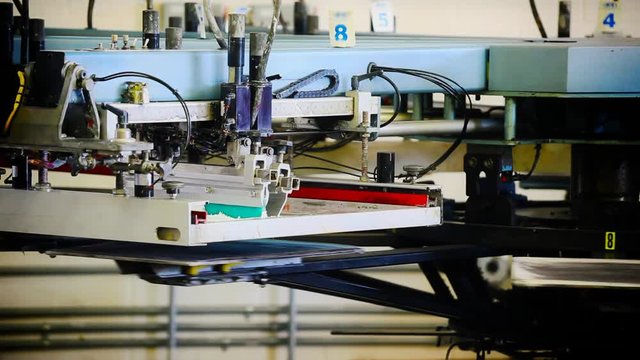 A pneumatic silk screening printing press operates.