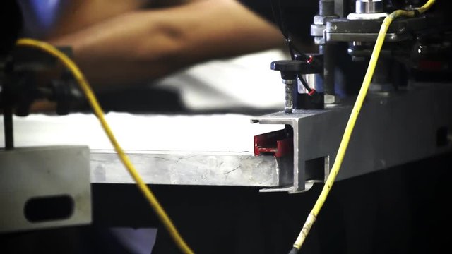 A pneumatic silk screening printing press operates.