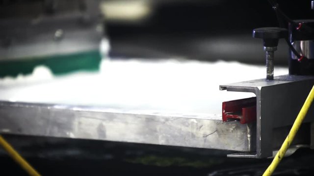 A pneumatic silk screening printing press operates.