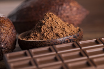 Chocolate bar, candy sweet, cacao beans and powder on wooden bac