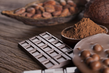 Chocolate bar, candy sweet, cacao beans and powder on wooden bac