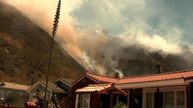A hillside fire burns over a hillside threatening a residential community. HD 1080.