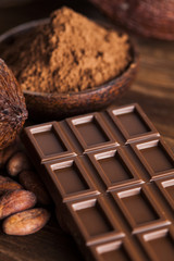 Chocolate bar, candy sweet, cacao beans and powder on wooden bac