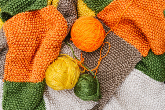 Three yellow, orange and green balls of wool on color wool fabri