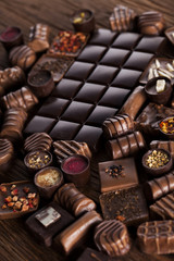Chocolate bars and pralines on wooden background