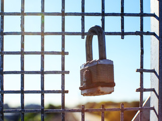 lock on the grid against a blue sky. padlock hanging in the lattice opening. the concept of freedom